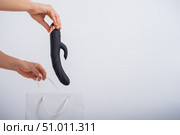 A woman makes a purchase and puts a dildo in a bag on a white background. Close-up of female hands with a black vibrator. Стоковое фото, фотограф Михаил Решетников / Фотобанк Лори