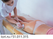 Woman in a beauty salon. Ultrasonic massage of the female buttocks and hips against cellulite and excess weight. Hardware figure correction. The doctor conducts the cavitation procedure for the girl. Стоковое фото, фотограф Михаил Решетников / Фотобанк Лори