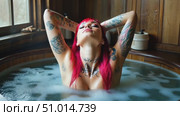 A tattooed individual enjoys a calming soak in a rustic hot tub, surrounded by wooden decor and bubbling water, creating a peaceful atmosphere. Стоковое AI-видео, аниматор Данила Большаков / Фотобанк Лори