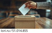 A person casts a ballot into a cardboard box during a local election, highlighting civic engagement and the voting process. Стоковое AI-видео, аниматор Данила Большаков / Фотобанк Лори