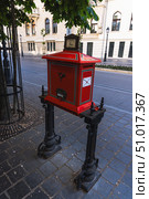 A vivid red vintage postbox stands on a cobblestone street. Редакционное фото, фотограф Виктор Ветошкин / Фотобанк Лори