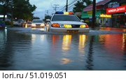A police car drives through deep floodwaters on a downtown street as heavy rain continues, creating challenging conditions for motorists. Стоковое AI-видео, аниматор Данила Большаков / Фотобанк Лори