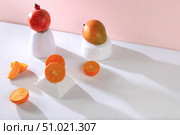 Modern still life with citrus, orange juice and oranges, pomegranate and mango on stand and podiums on pink background with long hard shadows, minimal detox diet concept, summer vitamin drinks, selective focus. Стоковое фото, фотограф Светлана Балынь / Фотобанк Лори