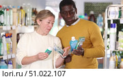 African man and European wife decided to buy dental care kit, looking for something in window. Стоковое видео, видеограф Яков Филимонов / Фотобанк Лори
