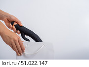 A woman makes a purchase and puts a dildo in a bag on a white background. Close-up of female hands with a black vibrator. Стоковое фото, фотограф Михаил Решетников / Фотобанк Лори