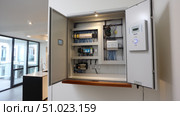 Electrical room with multiple smart meters, cabinets, wiring and fire extinguisher. Below-grade service room strata building with residential or commercial units. Selective focus. Стоковое AI-изображение, AI-художник ALLA YURTAYEVA / Фотобанк Лори