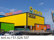 Magnitogorsk, Russian Federation - August 05, 2025: Brightly colored Lenta supermarket building with DNS sign, showcasing vibrant architecture and modern retail environment in urban setting. Редакционное фото, фотограф Ирина Ручушкина / Фотобанк Лори