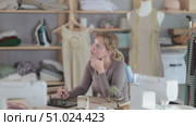 Thoughtful female fashion designer sitting at work table in studio. Стоковое видео, видеограф Яков Филимонов / Фотобанк Лори