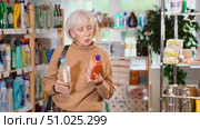 Uncertain mature female buyer choosing convenient unclogging agent in department store. Стоковое видео, видеограф Яков Филимонов / Фотобанк Лори