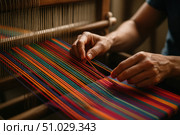 Hands Weaving Colorful Mexican Textile on Loom.  Close-up of artisan hands weaving vibrant multicolored threads on a traditional loom to create a Mexican textile pattern. Стоковое AI-изображение, AI-художник Башкирова Анна / Фотобанк Лори