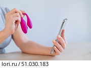 A woman demonstrates a modern curved clitoral vaginal vibrator in her video blog on her smartphone. Girl advise sex toy. Стоковое фото, фотограф Михаил Решетников / Фотобанк Лори