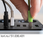 Modern convenient multi-port usb charger for devices. Close-up of a female hand plugging multi-colored cables into a power outlet. Macro. Стоковое фото, фотограф Михаил Решетников / Фотобанк Лори