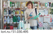 Store visitor woman purchases in household chemicals department, choose multisurface cleaner spray. Стоковое видео, видеограф Яков Филимонов / Фотобанк Лори