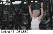 Aspiring older woman training in contemporary fitness center, using lat pulldown machine to strengthen back, arms, and improve upper body posture and muscle control, staying active and healthy. Стоковое видео, видеограф Яков Филимонов / Фотобанк Лори