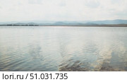 Bashkortostan, Russian Federation - August 07, 2025: Aerial view of tranquil lake reflecting clouds and mountains, showcasing serene landscape with lush greenery and open sky. Редакционное видео, видеограф Ирина Ручушкина / Фотобанк Лори