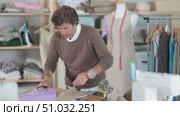 Adult male tailor cutting fabric with scissors in sewing workshop. Стоковое видео, видеограф Яков Филимонов / Фотобанк Лори