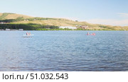 Lake Bannoe, Russian Federation - July 31, 2025: Two individuals paddleboarding on a serene lake surrounded by rolling hills and lush greenery, showcasing outdoor adventure and tranquility. Редакционное видео, видеограф Ирина Ручушкина / Фотобанк Лори
