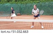Girl plays tennis on open court with opponent. Player hits ball with racket, serves ball, and practices actively. Стоковое видео, видеограф Яков Филимонов / Фотобанк Лори