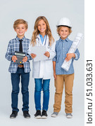 Three children dressed as professionals, one with a calculator, another in a hard hat and goggles, and the last holding blueprints, showcasing future career aspirations and teamwork. Стоковое AI-изображение, AI-художник Ирина Ручушкина / Фотобанк Лори