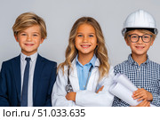 Three children dressed as professionals, one with a calculator, another in a hard hat and goggles, and the last holding blueprints, showcasing future career aspirations and teamwork. Стоковое AI-изображение, AI-художник Ирина Ручушкина / Фотобанк Лори