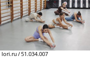 Group of girls in gym do stretching, sitting on floor and bending towards legs. Стоковое видео, видеограф Яков Филимонов / Фотобанк Лори