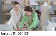 Female seamstresses drafting clothing pattern on paper in sewing workshop. Стоковое видео, видеограф Яков Филимонов / Фотобанк Лори