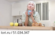 Cheerful senior woman holding mug of fresh coffee, having hot drink for breakfast. Стоковое видео, видеограф Яков Филимонов / Фотобанк Лори