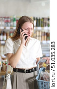 Angry young woman buyer choosing food in grocery store while talking on mobile phone. Стоковое видео, видеограф Яков Филимонов / Фотобанк Лори