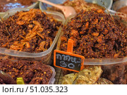 A close-up of containers of traditional Asian spicy paste made from dried shrimp and chili peppers displayed at a market. The vibrant texture of the mixture with red pepper flakes and seafood pieces conveys the richness of the flavor and spiciness of the dish. A price sign in Thai adds to the street market atmosphere. Стоковое фото, фотограф Анна Кривицкая / Фотобанк Лори