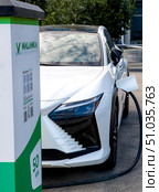 The white electric car is being charged at the charging station. Belarus. Minsk. 09.08.25. Редакционное фото, фотограф Ярославский Максим / Фотобанк Лори