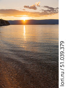 Scenic sunset on Baikal Lake. View of the pebble beach of the Small Sea with clean transparent water near Olkhon Island on quiet August evening. Picturesque seascape. Natural background. Summer travel. Стоковое фото, фотограф Виктория Катьянова / Фотобанк Лори