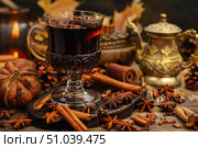 Glass of mulled wine with spices and christmas decorations creating festive atmosphere. Стоковое AI-изображение, AI-художник Иван Рябоконь / Фотобанк Лори