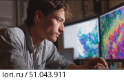 Young man analyzes colorful data on multiple screens in a dimly lit workspace in the evening. Стоковое AI-видео, аниматор Сергей Толмачёв / Фотобанк Лори