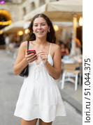 In evening, smiling girl with smartphone walks along city street Placa Real. Стоковое фото, фотограф Яков Филимонов / Фотобанк Лори