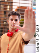 Serious young man with headphones making a stop gesture with his hand outdoors. Стоковое фото, фотограф Raquel Corcoles Mendez / Фотобанк Лори