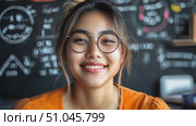 A bright young woman poses with a warm smile at her desk in a vibrant study space adorned with motivational messages and a friendly atmosphere. Стоковое AI-видео, аниматор Данила Большаков / Фотобанк Лори