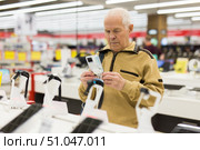 elderly man examines tablet computer in showroom of electronics store. Стоковое фото, фотограф Татьяна Яцевич / Фотобанк Лори