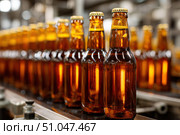 Beer Bottling plant. Brown Beer Bottles in rows. Bottling process in modern factory. Capped Glass Beer Bottles ready for distribution in a brewery. Manufacturing. Production of beer in a glass bottle. Стоковое AI-изображение, AI-художник Марина Демидюк / Фотобанк Лори