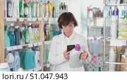Checking expiration date of detergent - female shopper scans QR code on label of detergent using her smartphone. Стоковое видео, видеограф Яков Филимонов / Фотобанк Лори