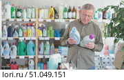 Senior man buyer select and studies label, read composition of liquid detergent. Client examine product, make purchase decision and discusses advantages and properties of product. Стоковое видео, видеограф Яков Филимонов / Фотобанк Лори