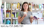 Young woman choosing a set of scented paraffin candles and a soy wax candle. Brunette woman buys candles for the comfort of her home. Стоковое видео, видеограф Яков Филимонов / Фотобанк Лори