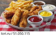 Crispy chicken tenders, french fries, and dipping sauces on checkered tablecloth. Стоковое AI-видео, аниматор Юрий Поздников / Фотобанк Лори