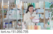 Attentive middle-aged woman scanning barcode on feminine pads in chemist's shop. Стоковое видео, видеограф Яков Филимонов / Фотобанк Лори