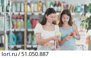 Interested preteen girl with mother in summer outfits examining two insect repellent products in supermarket, carefully deciding between spray and lotion for best protection. Стоковое видео, видеограф Яков Филимонов / Фотобанк Лори