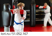 Karate practitioner striking mannequin bag in dojo. Стоковое фото, фотограф Яков Филимонов / Фотобанк Лори