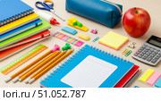 Back to school supplies on wooden desk background with colorful stationery for education concept. Student equipment including notebooks, pencils, calculator and apple for learning. Стоковое AI-изображение, AI-художник Павел Муравьев / Фотобанк Лори