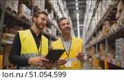 Warehouse workers review inventory and discuss logistics in a busy distribution center. Стоковое AI-видео, аниматор Сергей Толмачёв / Фотобанк Лори