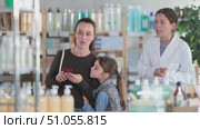 Happy mother with daughter scrolling phone while looking for something, pharmacist consulting her in drugstore. Стоковое видео, видеограф Яков Филимонов / Фотобанк Лори