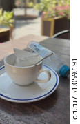 Empty coffee cup on saucer with spoon and plastic bottle on wooden table outdoors. Стоковое видео, видеограф Анастасия Золотницкая / Фотобанк Лори
