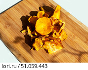 Vibrant yellow chanterelle mushrooms arranged on wooden cutting board, showcasing their unique shapes and textures, vegetarian culinary inspiration and gourmet cooking, Cantharellus cibarius, girolle. Стоковое фото, фотограф Елена Гоосен / Фотобанк Лори